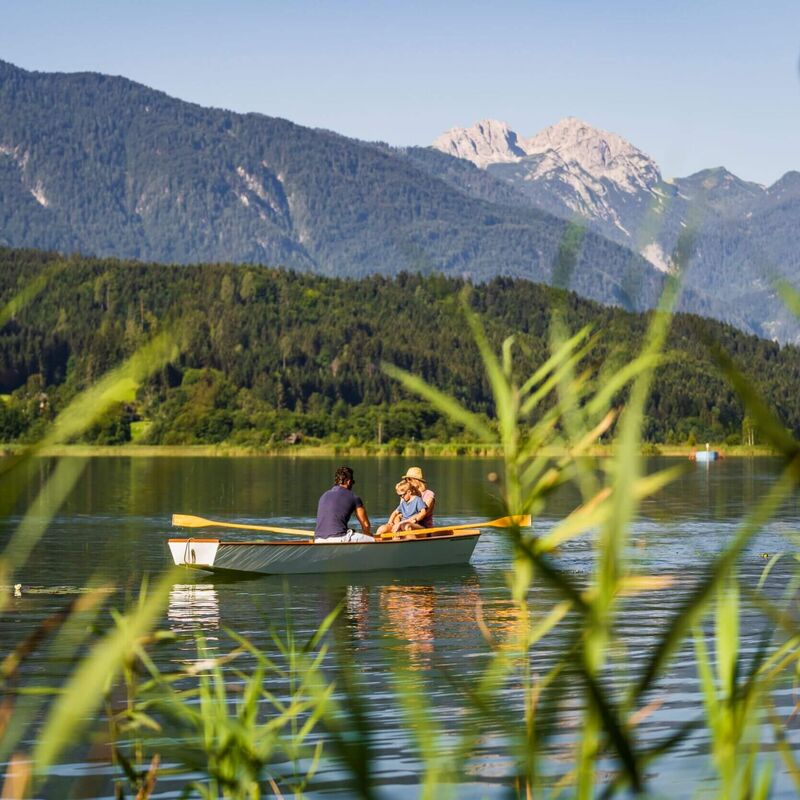Bootsfahrt am Pressegger See mit klarem Wasser, Badesteg und sommerlicher Berglandschaft