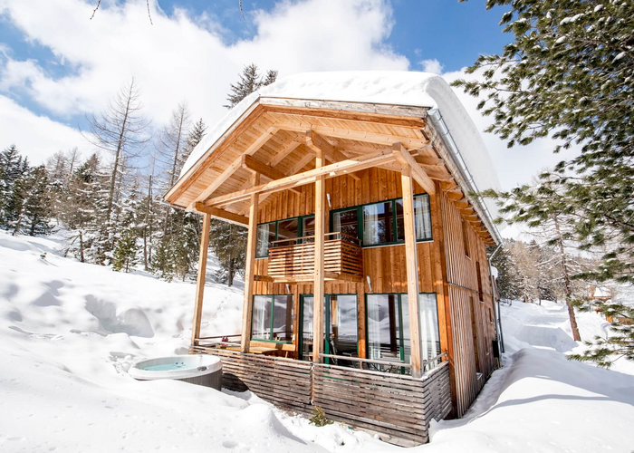Ferienhaus in Schnee bedeckter Waldlandschaft und Hot Tub