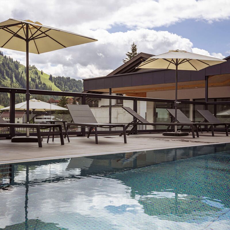 Outdoor pool with parasols and loungers at the Jagdhaus at Bergresort Berwanger Hof