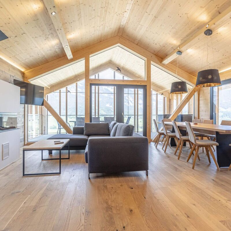 A stylish living area features modern furniture and large windows, showcasing a bright, open design in a premium chalet.