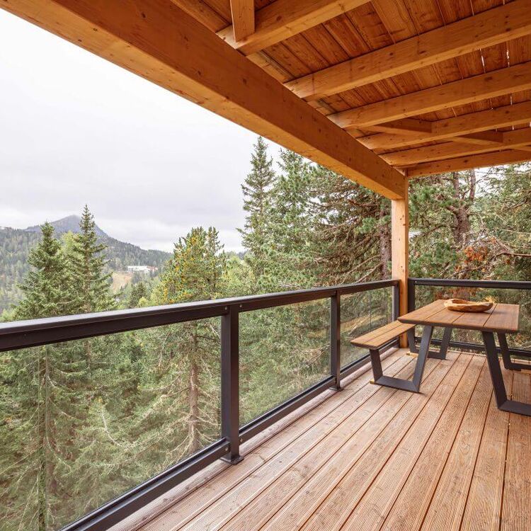 Eine gemütliche Terrasse im Bergresort bietet einen Blick auf den dichten Zirbenwald und die umliegenden Berge.