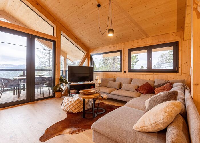 Gemütlicher Wohnbereich in einem Chalet auf der Turracher Höhe mit großem Sofa, Couchtisch und alpiner Einrichtung – ideal für einen Chaleturlaub in den Bergen.