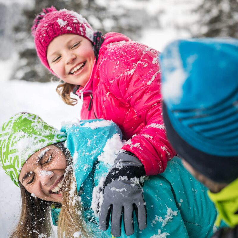 Eine Familie hat Spaß im Schnee, während Kinder fröhlich spielen und sich gegenseitig mit Schnee beworfen werden. | © Salzburger Land Tourismus