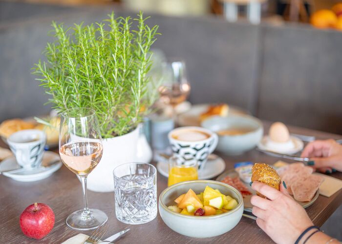 Ein schön gedeckter Tisch mit Frühstück, Obst, Getränken und frischen Brötchen in der ALPS KITCHEN Ehrwald.