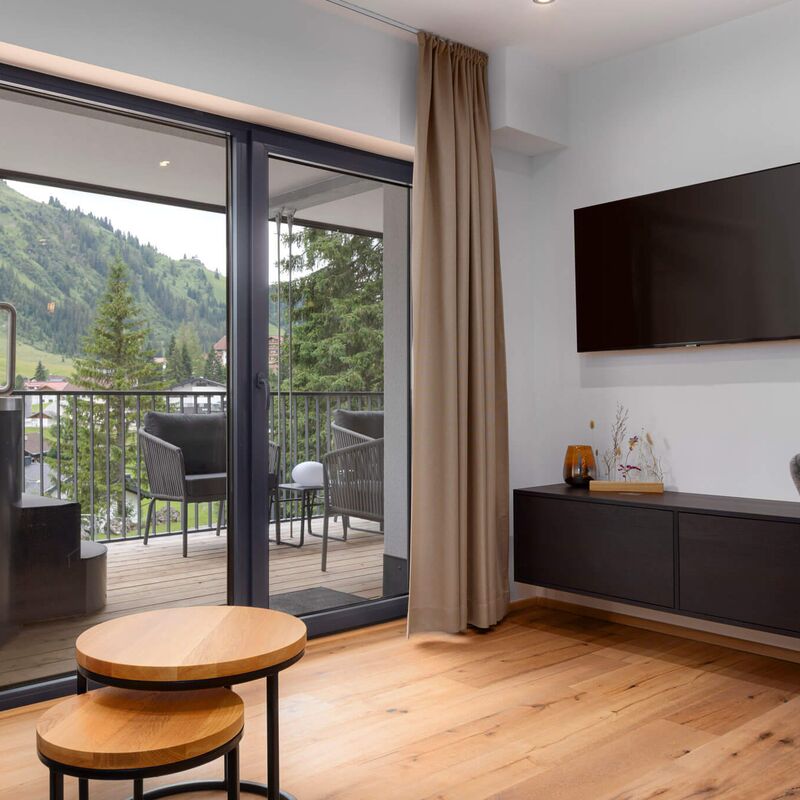 Blick vom Wohnbereich auf den Balkon mit Hot Tub und Berge