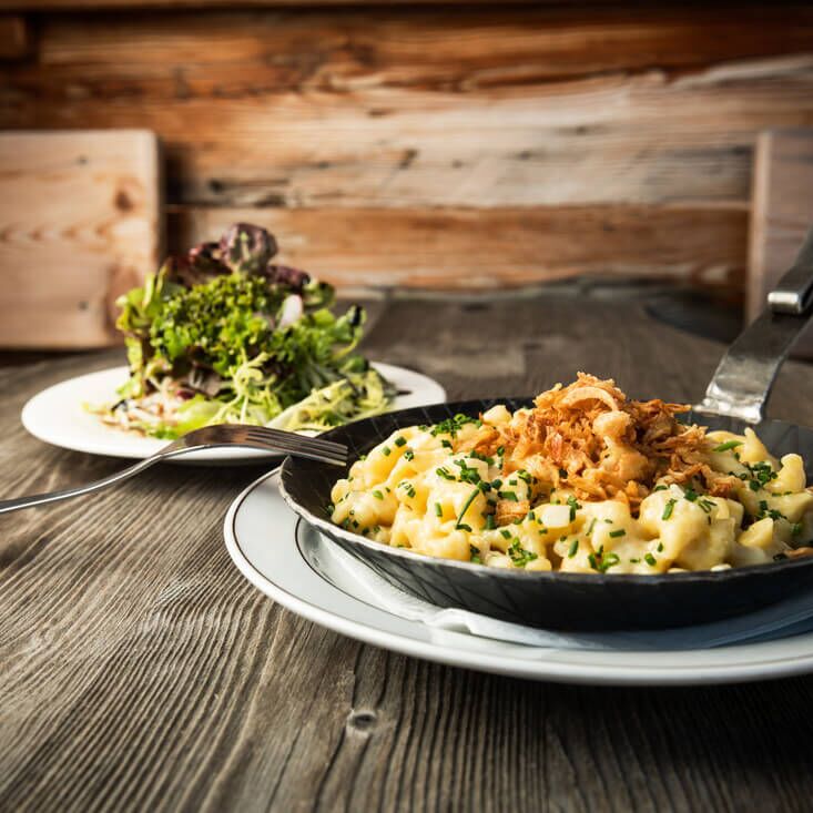 Käsespätzle mit braunem Butter und Zwiebeln in der gusseisernen Pfanne