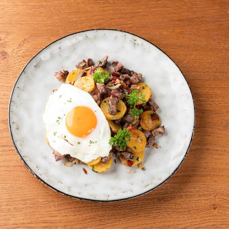 Plate with Tyrolean Gröstl and fried egg on a kitchen table