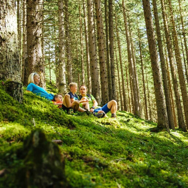 Parents resting with their 2 children on the mossy forest floor © TVB Rauris