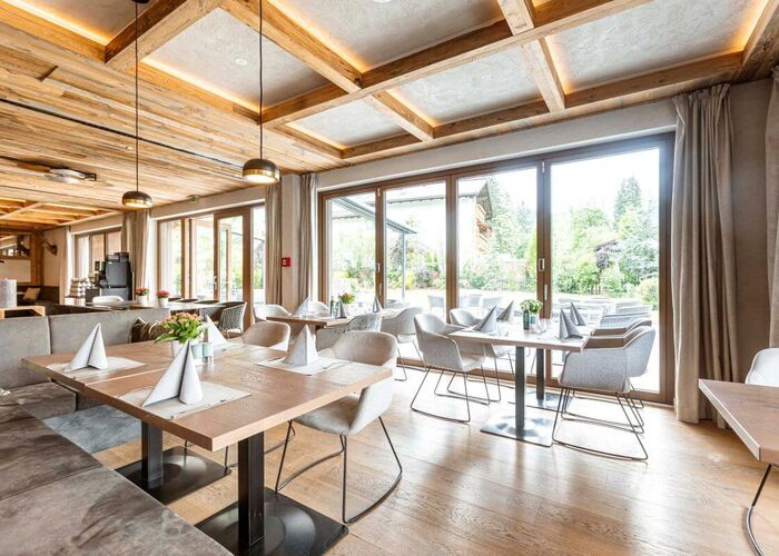 Moderne restaurantinrichting met glazen front, houten plafonds en sfeervolle tafels voor diners.