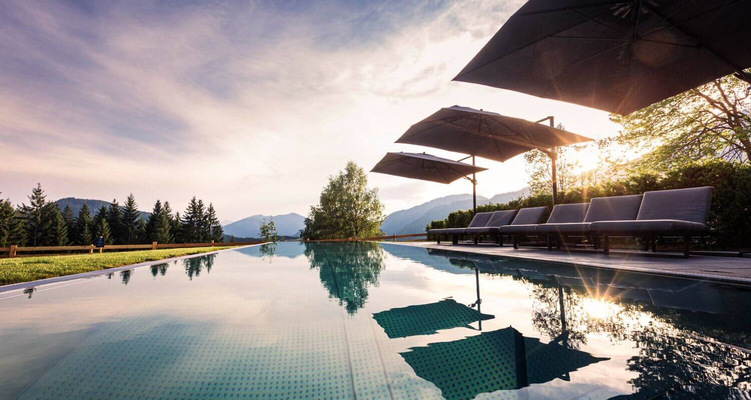 Outdoor pool with sun loungers, parasols and mountain views