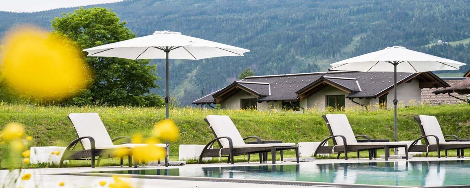 Outdoor Pool mit Sonnenliegen und Schirmen in der Tauernresidence Radstadt