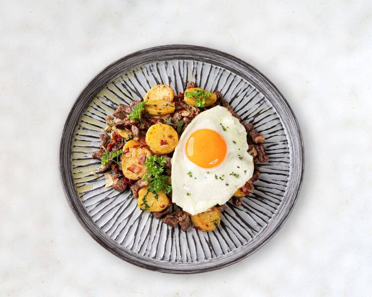 Bord vol Tiroler Gröstl met gebakken ei en rundvlees