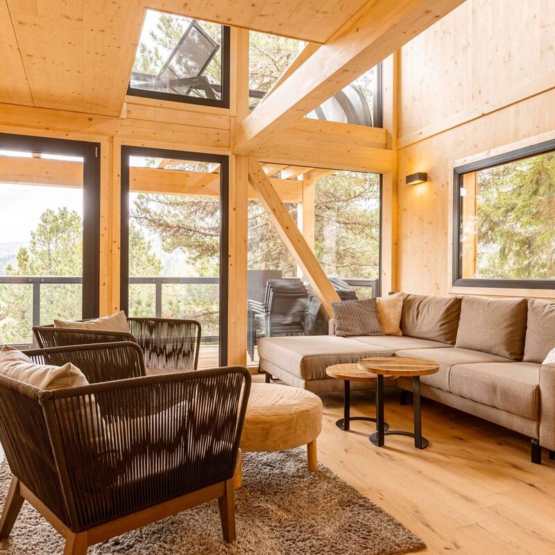 Cosy living area with glass front and view of the Swiss stone pine forest