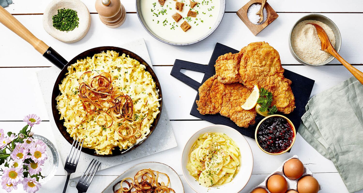 Zillertal dishes such as cheese spaetzle, schnitzel and traditional Austrian home-style food served on a rustic table. © Zillertal Tourismus / Kevin Ilse