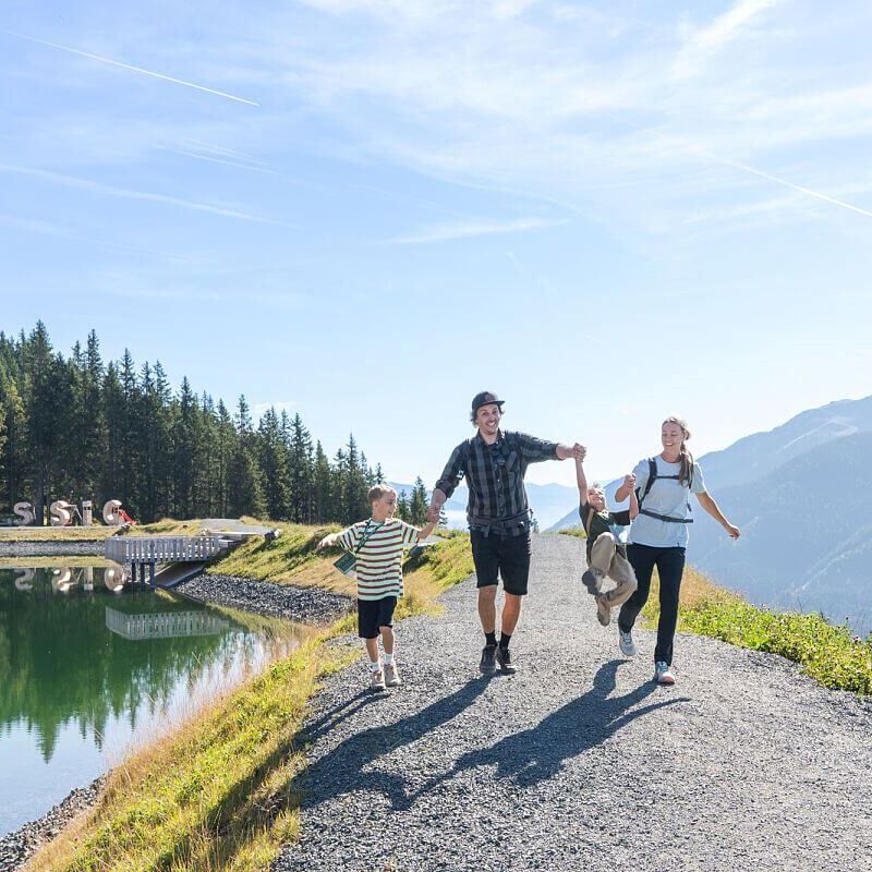 Familie wandert unbeschwert am Speicherteich in Saalbach Hinterglemm