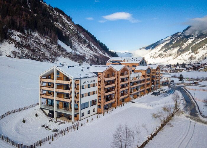 Exterior view of Carpe Solem Rauris in winter, surrounded by the snow-covered mountains of the Rauris Valley.