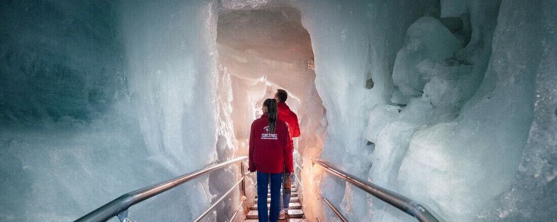 Pärchen wandert auf Treppen zwischen riesigen Eiswänden.