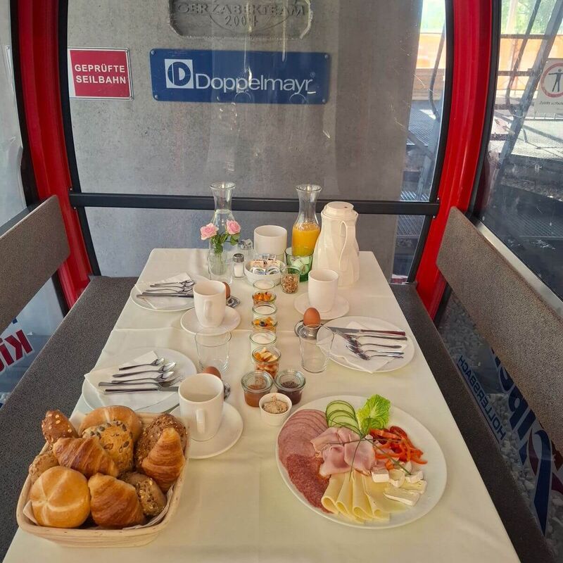Ein reichhaltiges Frühstück in einer Gondel, mit frischen Brötchen, Aufschnitt und Getränken, bereit zum Genießen.