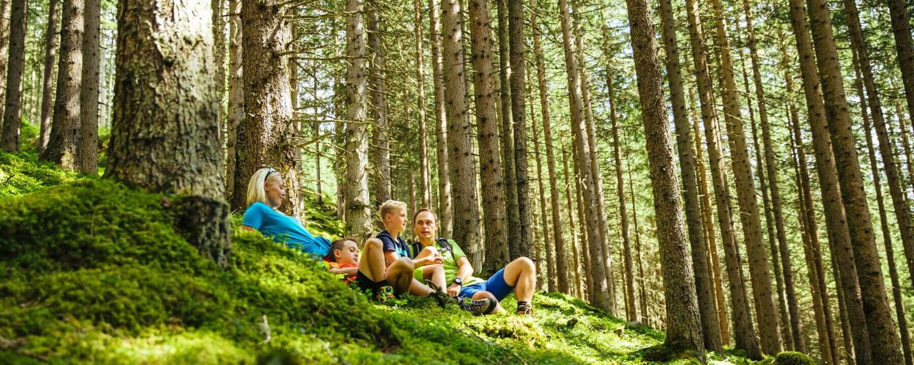 Eltern machen mit ihren 2 Kindern Rast am bemoosten Waldboden © TVB Rauris