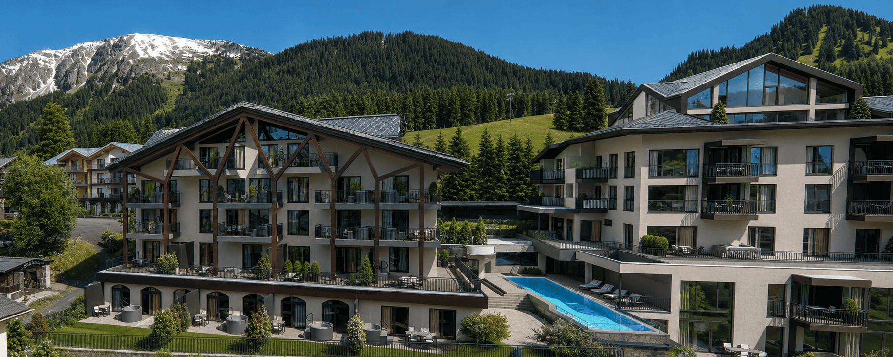 Außenansicht des Bergresort Berwanger Hof mit Pool, Balkonen und Blick auf die umliegende Berglandschaft.