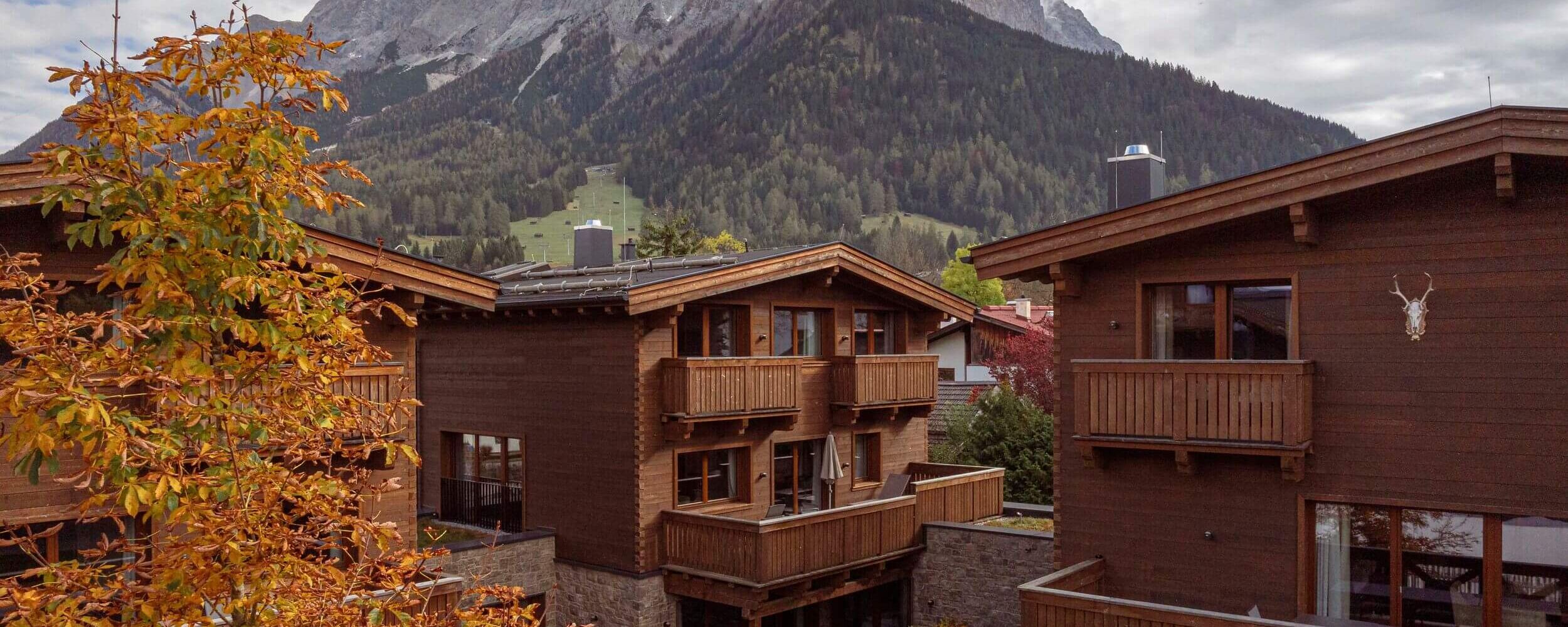 Een prachtig uitzicht op houten chalets met bergen en herfstkleuren in de achtergrond.