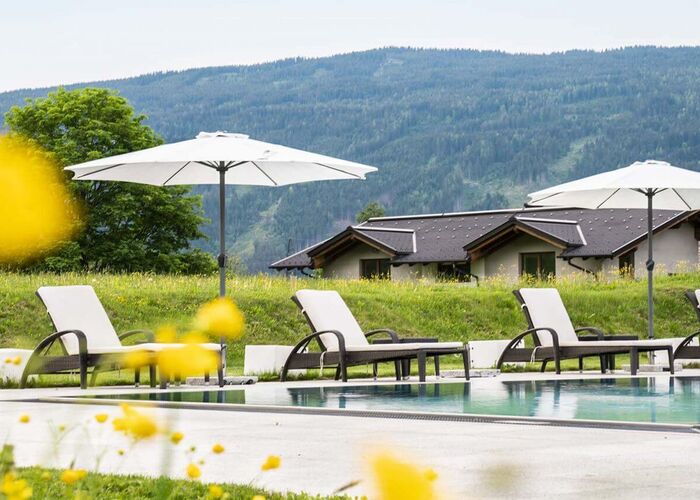 Outdoor Pool mit Sonnenliegen und Schirmen in der Tauernresidence Radstadt