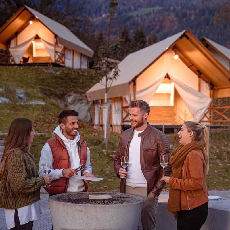 Two couples who are friends are having a barbecue and drinking a glass of wine.