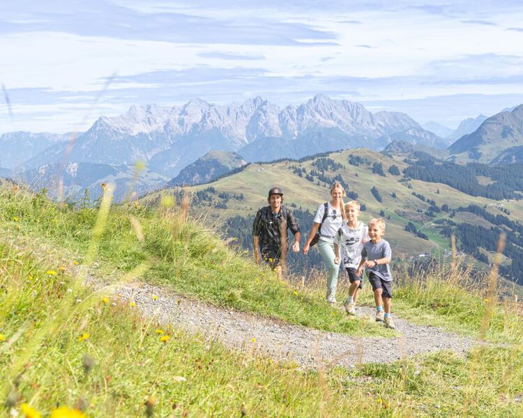 Family hiking in the mountains, with the Hochkönig in the background.
