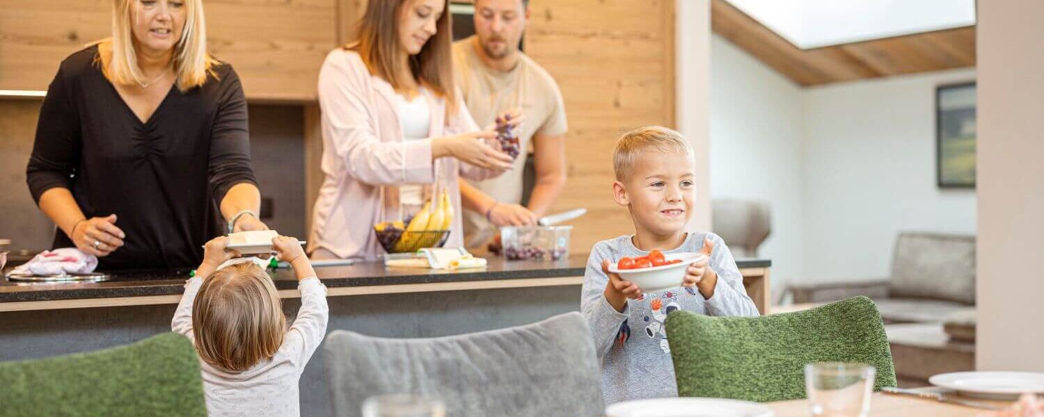 Oma, ouders en twee kinderen maken hun ontbijt klaar in het vakantieappartement.