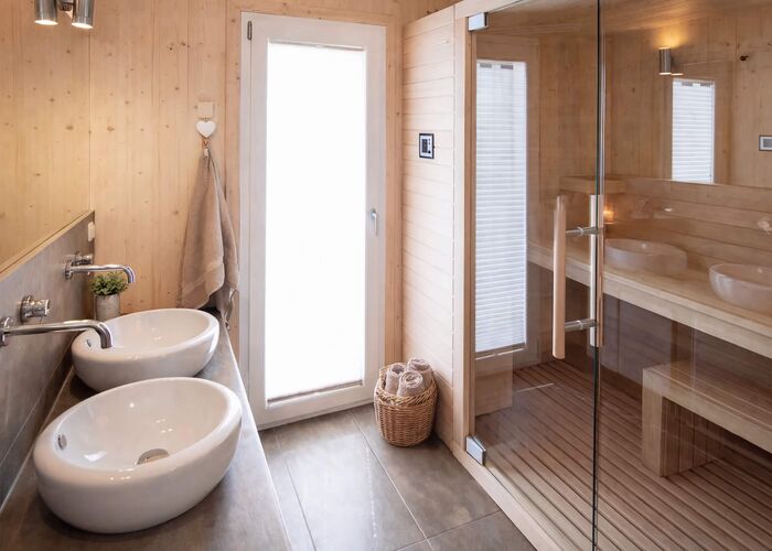 A modern bathroom features sleek sinks, wood accents, and a glass shower, creating a serene spa-like atmosphere.