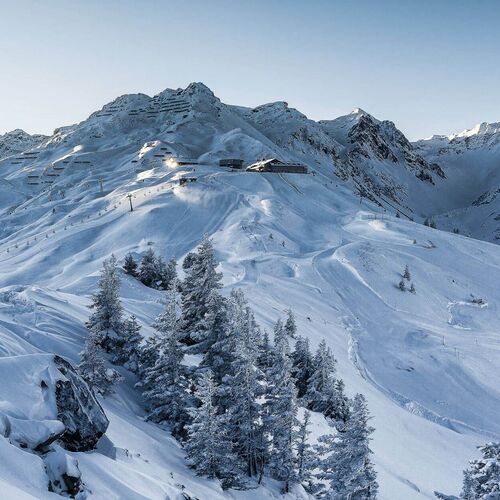 Winterlandschaft mit schneebedeckten Bergen und strahlender Sonne über einem Panorama in den Alpen. | © Nova