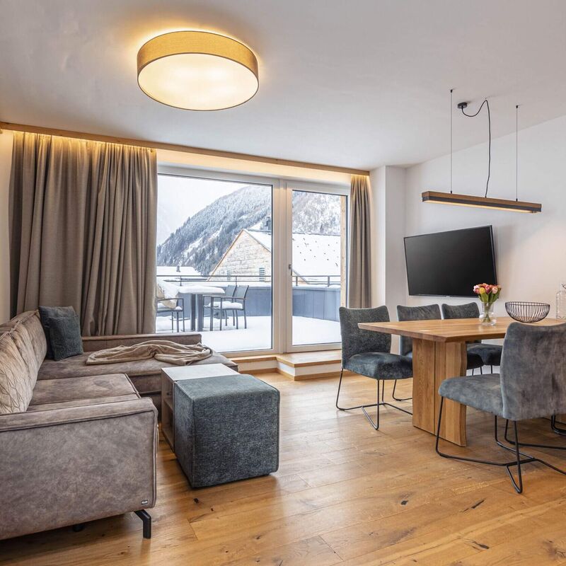 Wohn  & Essbereich einer Ferienwohnung mit Terrasse und Blick auf die verschneiten Berge