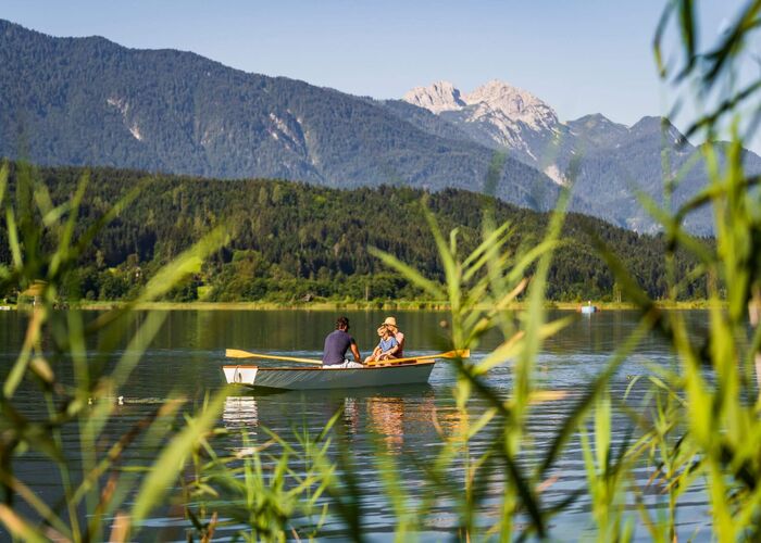 Bootsfahrt am Pressegger See mit klarem Wasser, Badesteg und sommerlicher Berglandschaft