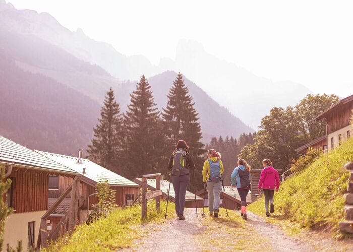Gruppe von Wanderern spaziert zwischen Ferienhäusern