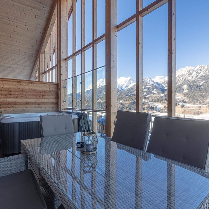 Gemütlicher Balkon mit Whirlpool, modernen Möbeln und Blick auf schneebedeckte Berge.