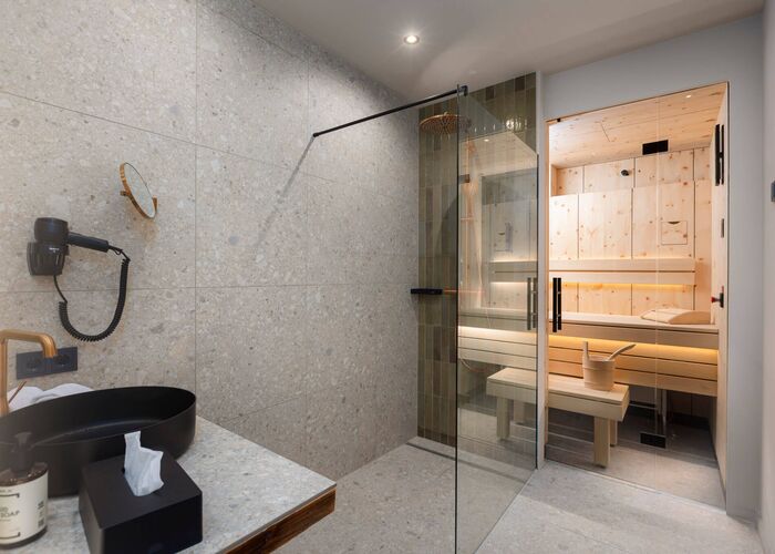 Bathroom with modern sinks and Finnish sauna in the background