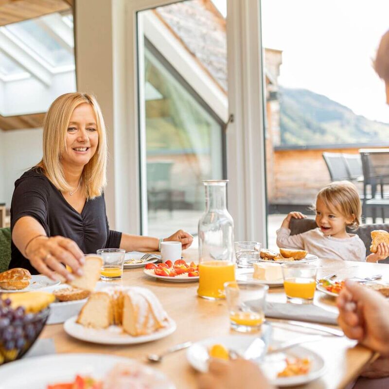 Familie mit Kind und Kleinkind sitzt am reich gedeckten Frühstückstisch.