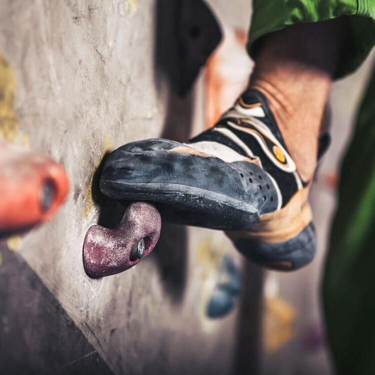 Close-up of a climbing shoe on a hold in an indoor climbing gym