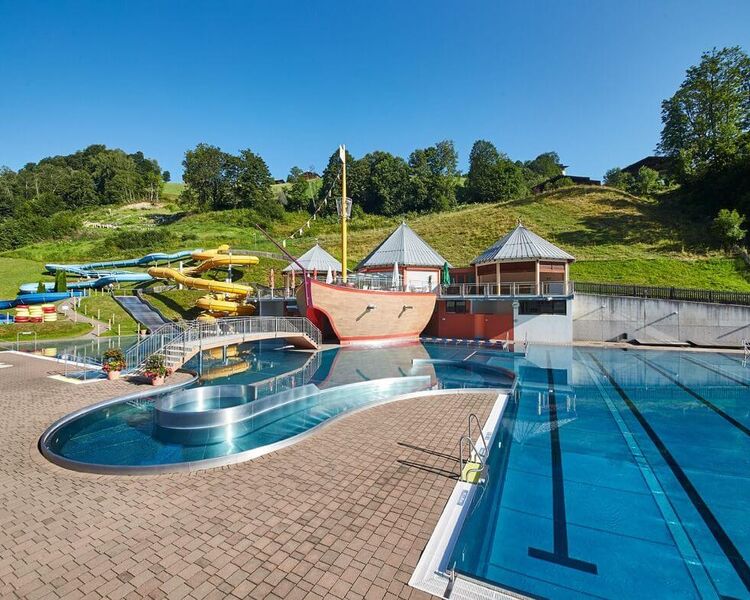 Outdoor pool with three water slides, pirate ship and sunbathing lawns.