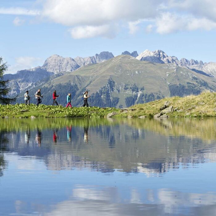 Hiker by a mountain lake in the Lesachtal Valley with a dramatic mountain backdrop near the Italian border