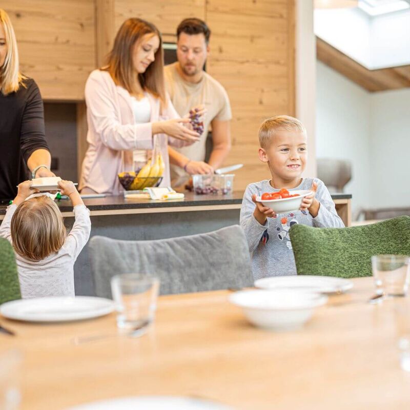Oma, ouders en twee kinderen maken hun ontbijt klaar in het vakantieappartement.