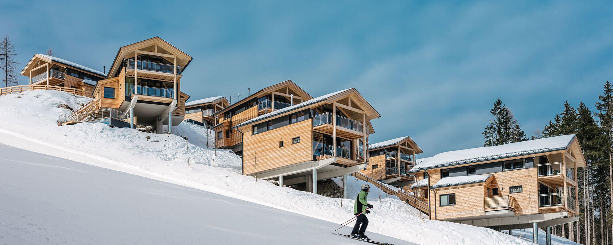 Ski slope with skiers and holiday homes in winter