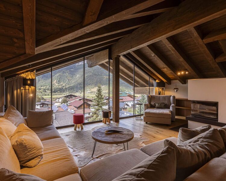 Large corner sofa, fireplace and comfortable armchair in a Tyrolean-style living room with a marvellous view