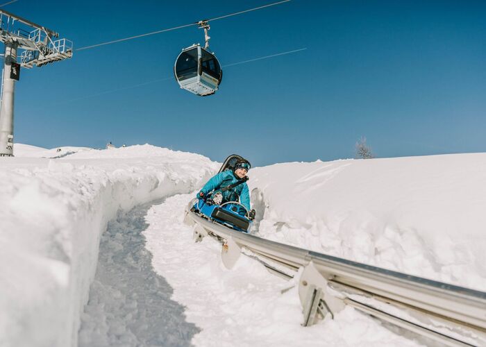 Mann fährt mit dem Nocky Flitzer durch verschneite Landschaft