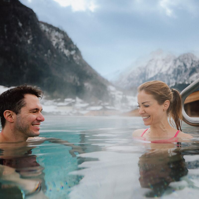 Pärchen entspannt im Infinity Pool mit Blick auf das Kitzsteinhorn