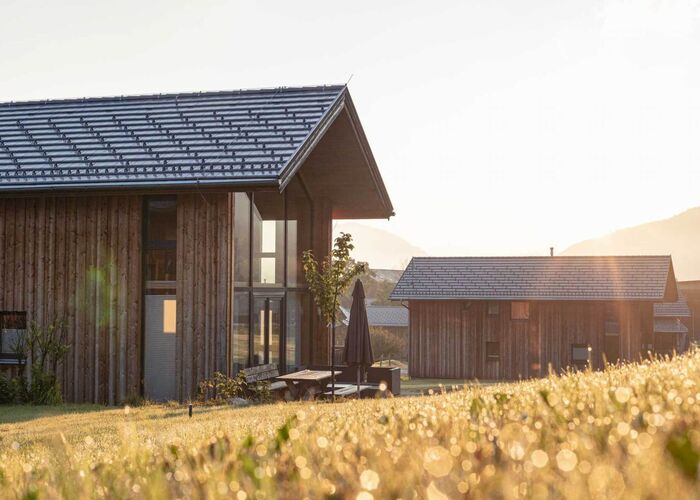 Die Kreischberg Chalets strahlen im Sonnenlicht, umgeben von sanften Hügeln und grünen Wiesen.