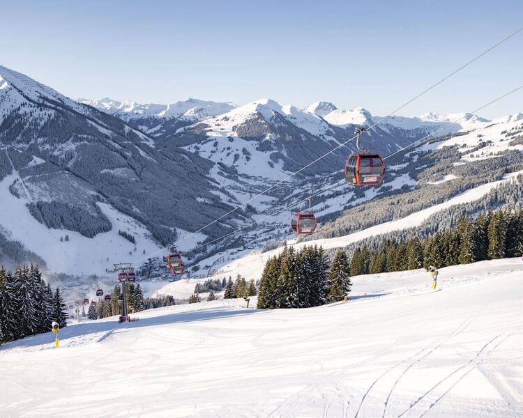 Gondelbahn Kohlmaisbahn mit frisch präparierter Piste, im Hintergrund das verschneite hintere Glemmtal.