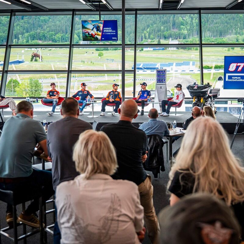 Podiumsdiskussion während einer Motorsportveranstaltung mit Fahrern und Publikum in modernem Ambiente | © Name