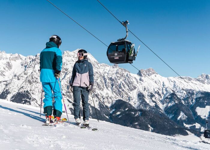 2 skiërs staan onder de Leogang Steinberg kabelbaan.