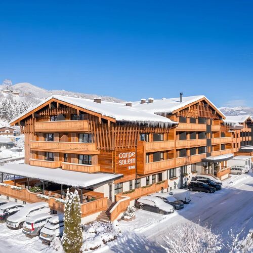 Winterliche Außenansicht des Carpe Solem Kaprun mit Schnee und Blick auf die umliegende Alpenlandschaft.